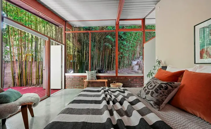 Primary bedroom of a Bel Air Mid Century Modern home with views of the bamboo grove