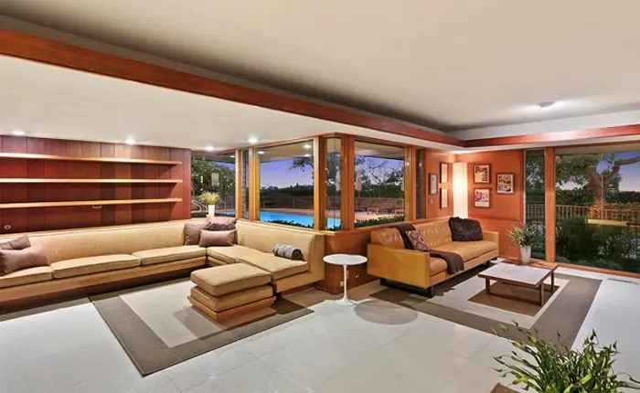 Interior of a James De Long Usonian home in Southern California showing mitered glass windows, natural wood built-ins and organic indoor-outdoor connection